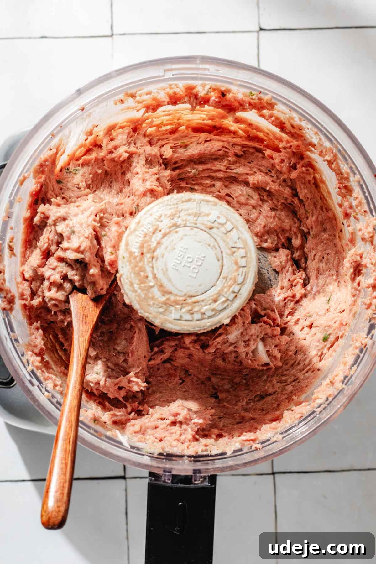 One-Pan Lamb and Beef Doner Kebab 8 The smoothly pureed doner kebab meat mixture, perfectly blended into a paste-like consistency, is visible inside a food processor bowl, with a wooden spoon resting on the side, ready for shaping on a white tiled background.