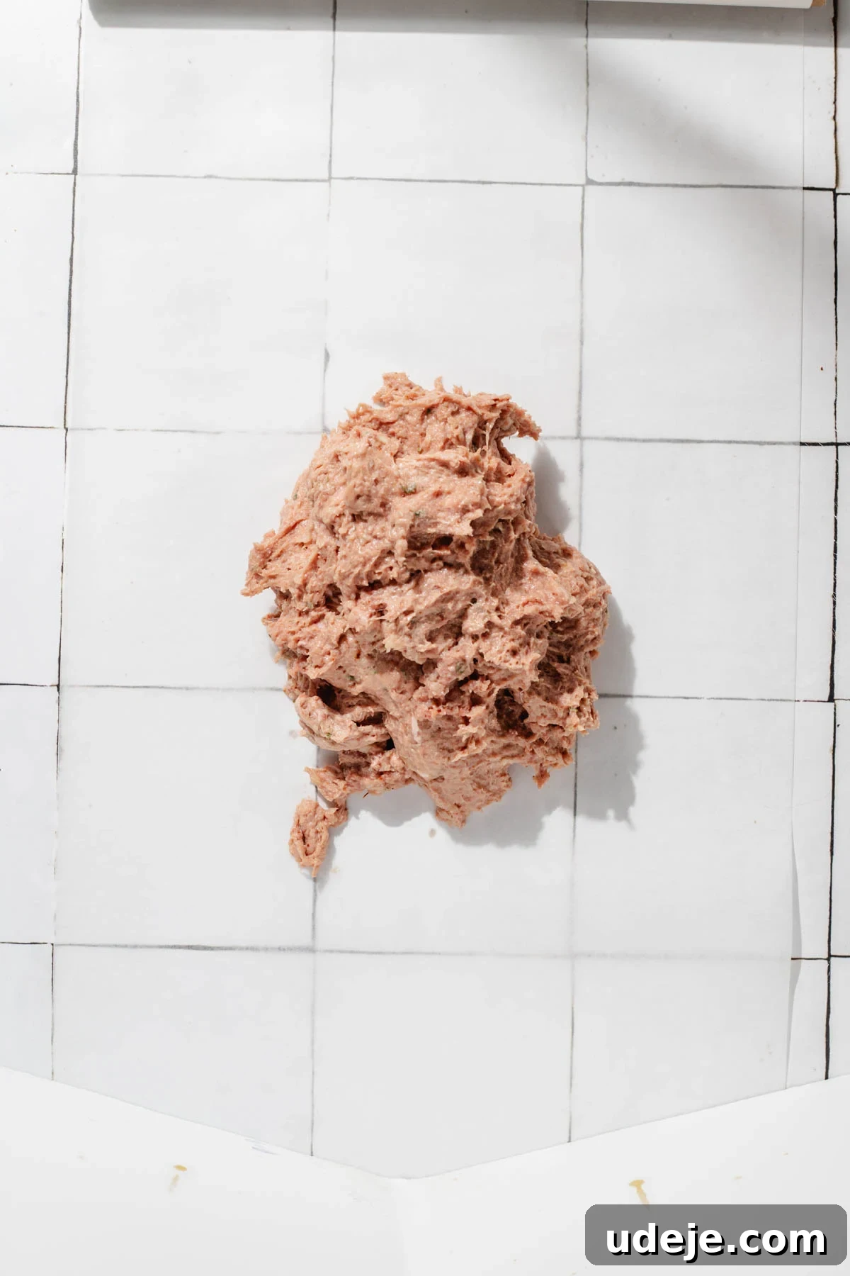 One-Pan Lamb and Beef Doner Kebab 9 The smooth doner kebab meat mixture is carefully spread onto a piece of parchment paper, ready for shaping into a log, positioned on a clean white tiled background.