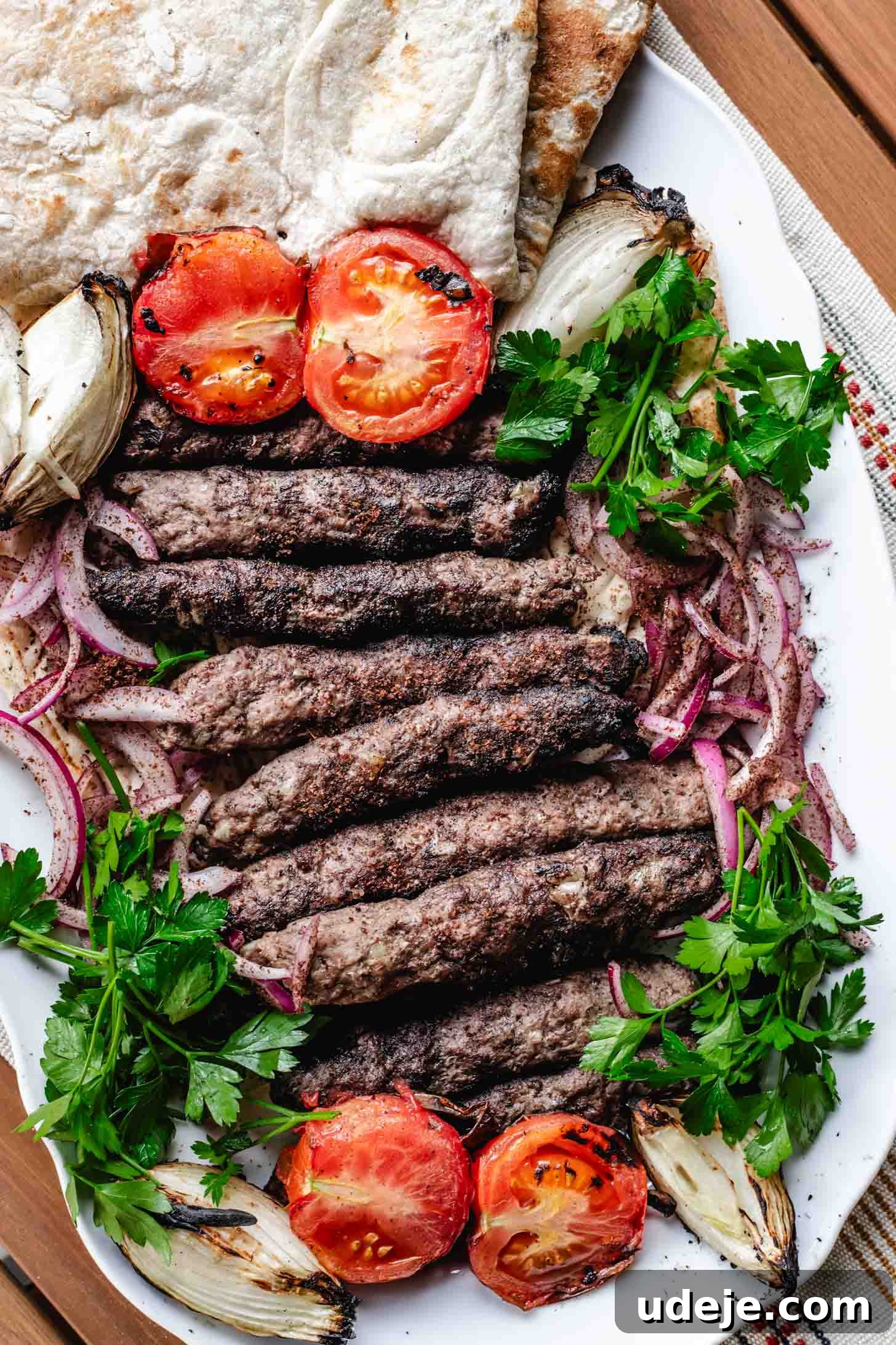 Sizzling Iraqi Kabab A Taste of Tradition 2 Grilled Iraqi kabab skewers are plated on a large white platter, along with sumac onions, parsley, grilled tomato, grilled onions and Iraqi bread. A complete and vibrant meal.