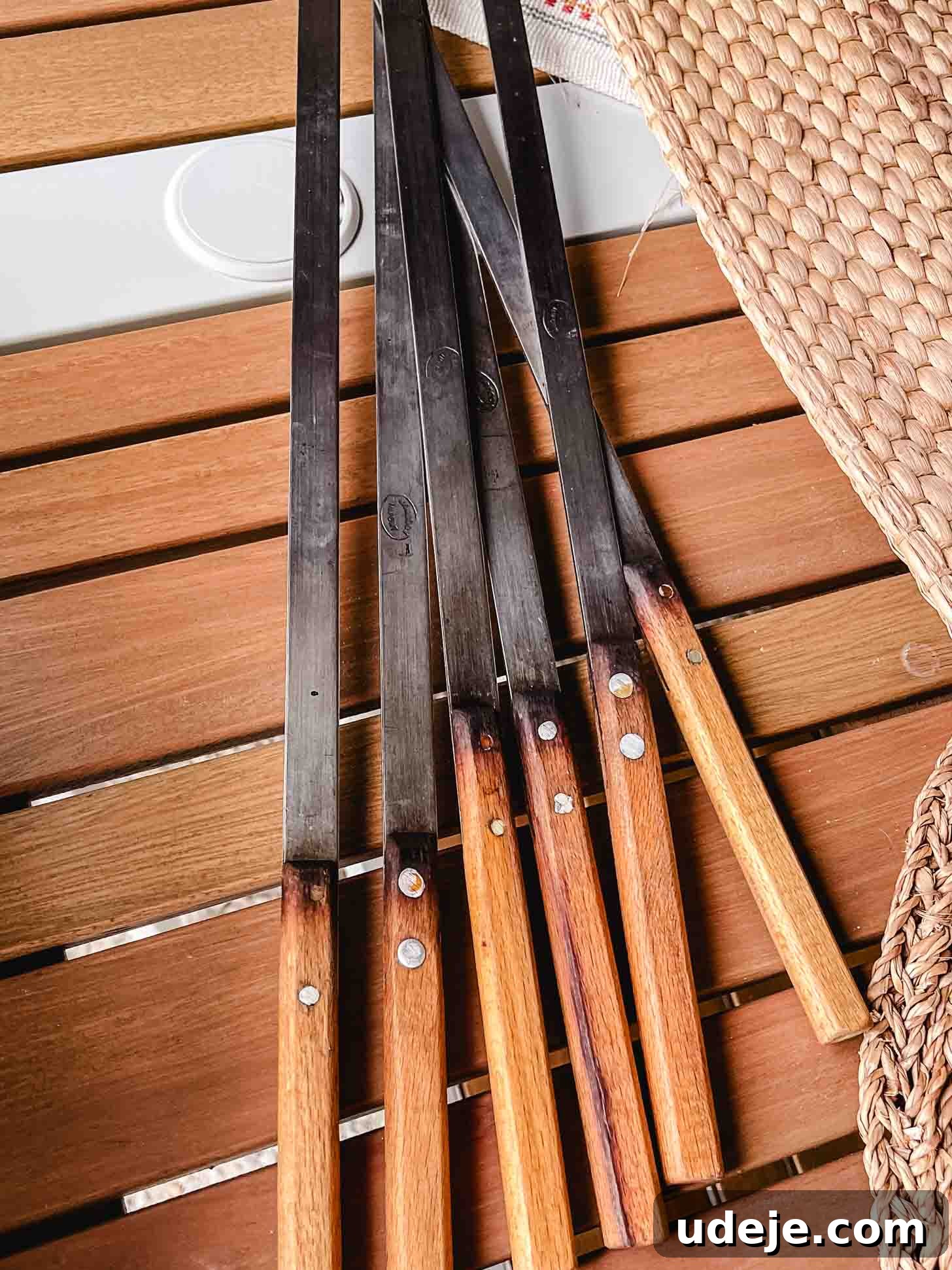 Sizzling Iraqi Kabab A Taste of Tradition 3 A photo of flat metal skewers with wooden handles on a wooden table, ready for kabab preparation.