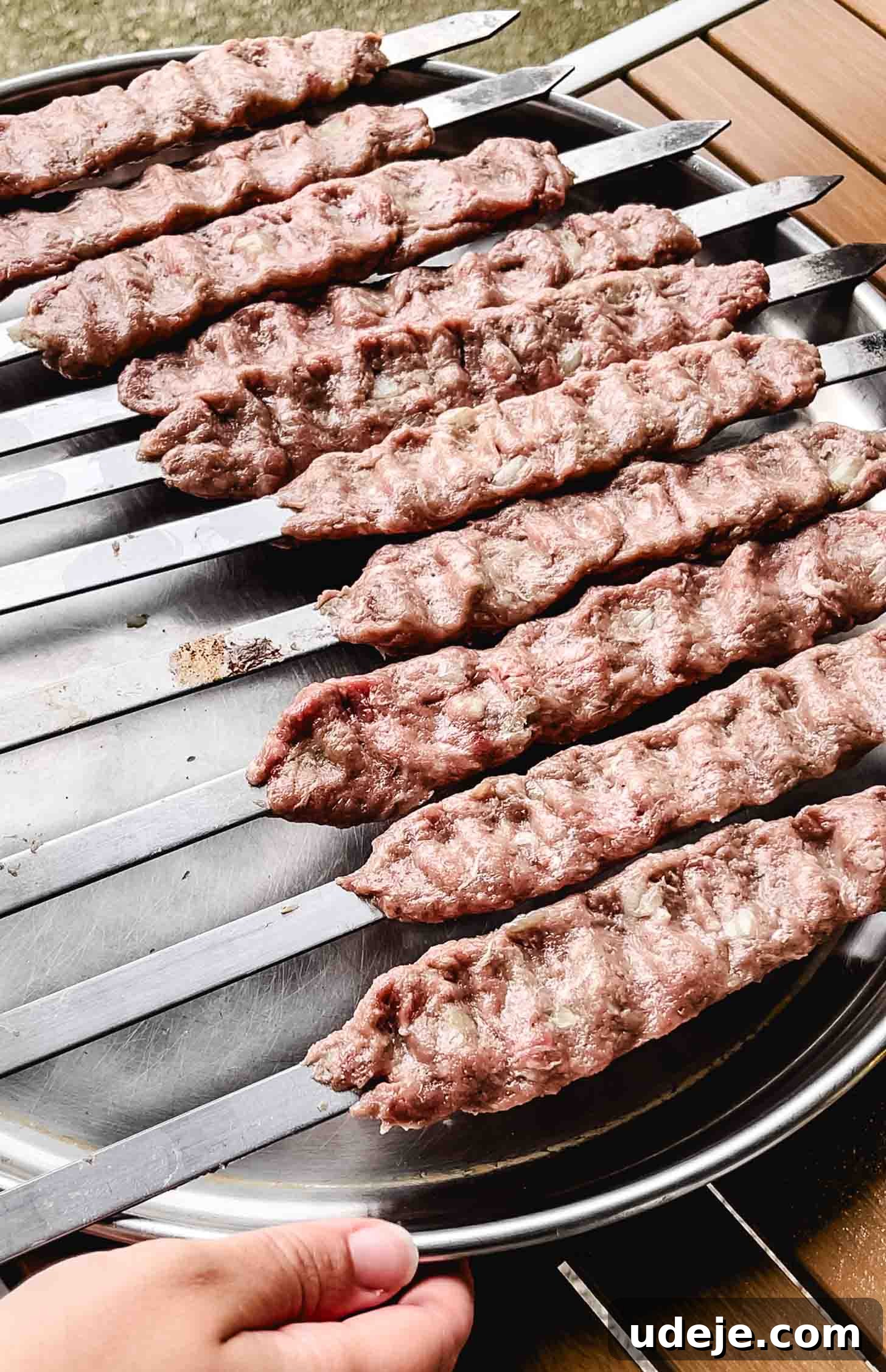 Sizzling Iraqi Kabab A Taste of Tradition 7 Ten raw Iraqi kabab skewers, expertly shaped and ready for the grill, placed on a large stainless steel tray.
