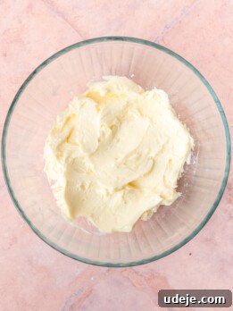 Creamed butter in a glass bowl on a light red tiled background.