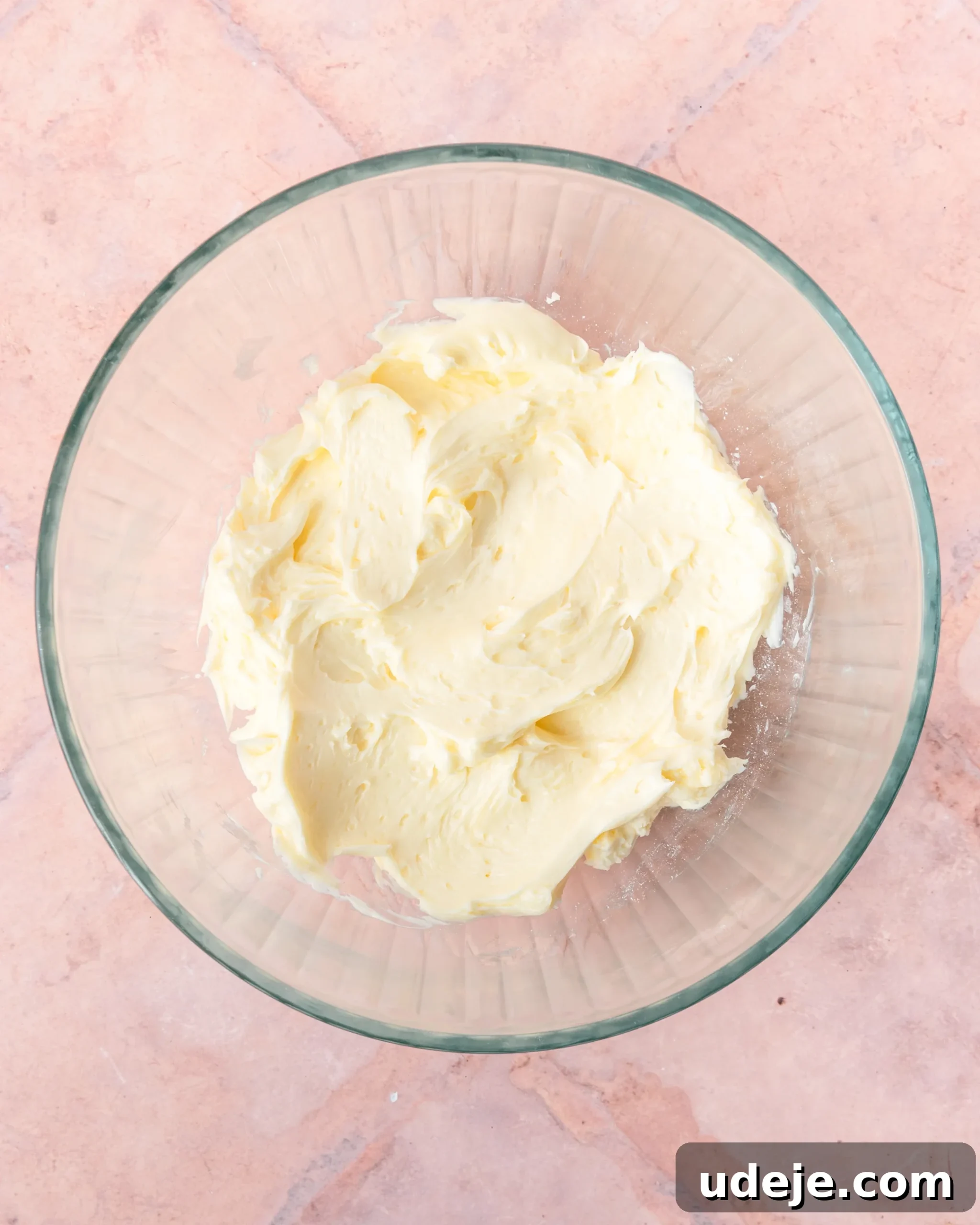 Fragrant Cardamom Shortbread Cookies 6 Creamed butter in a glass bowl on a light red tiled background.