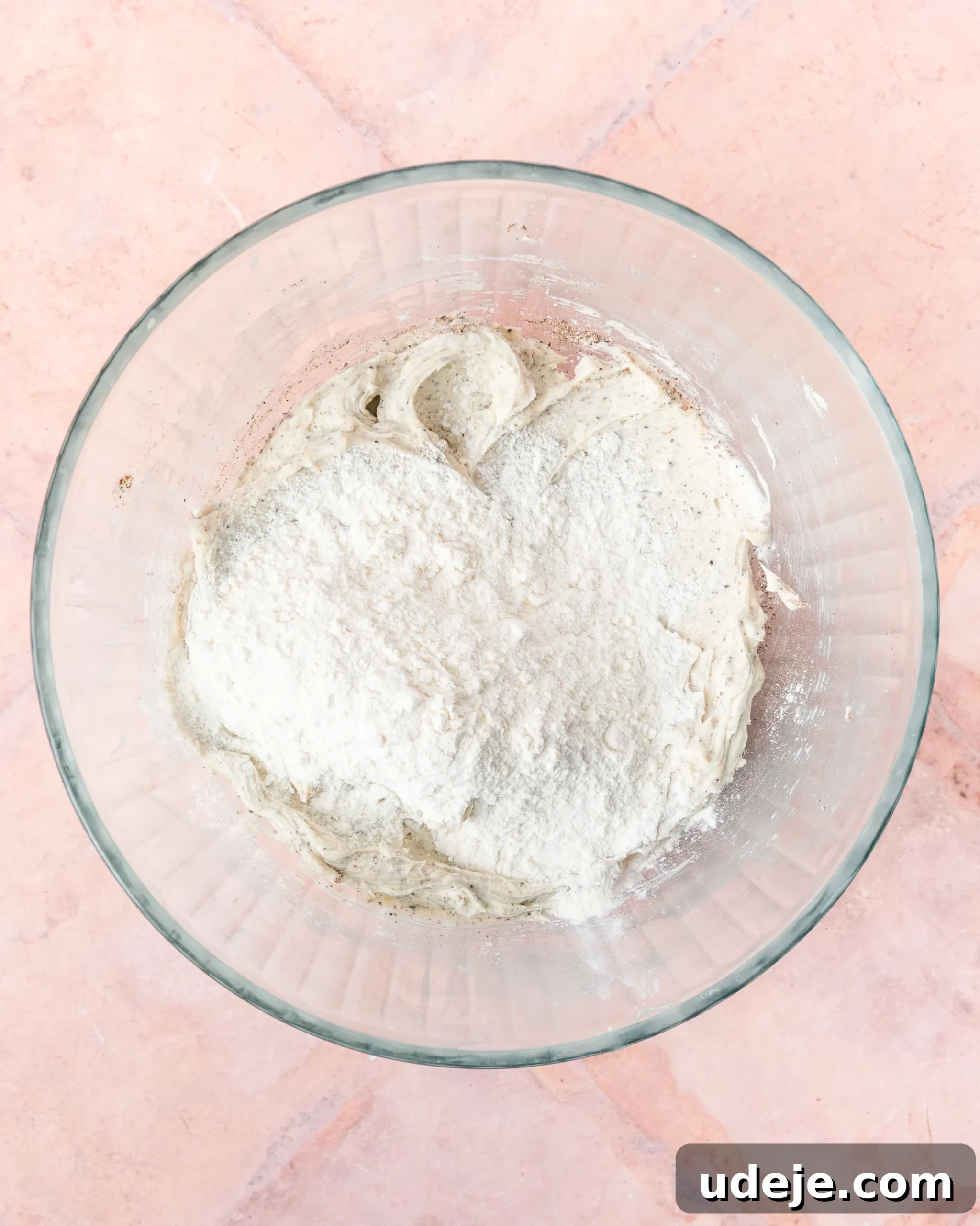 Fragrant Cardamom Shortbread Cookies 9 Creamed butter with cardamom and baking powder in a glass bowl with flour on a light red tiled background.