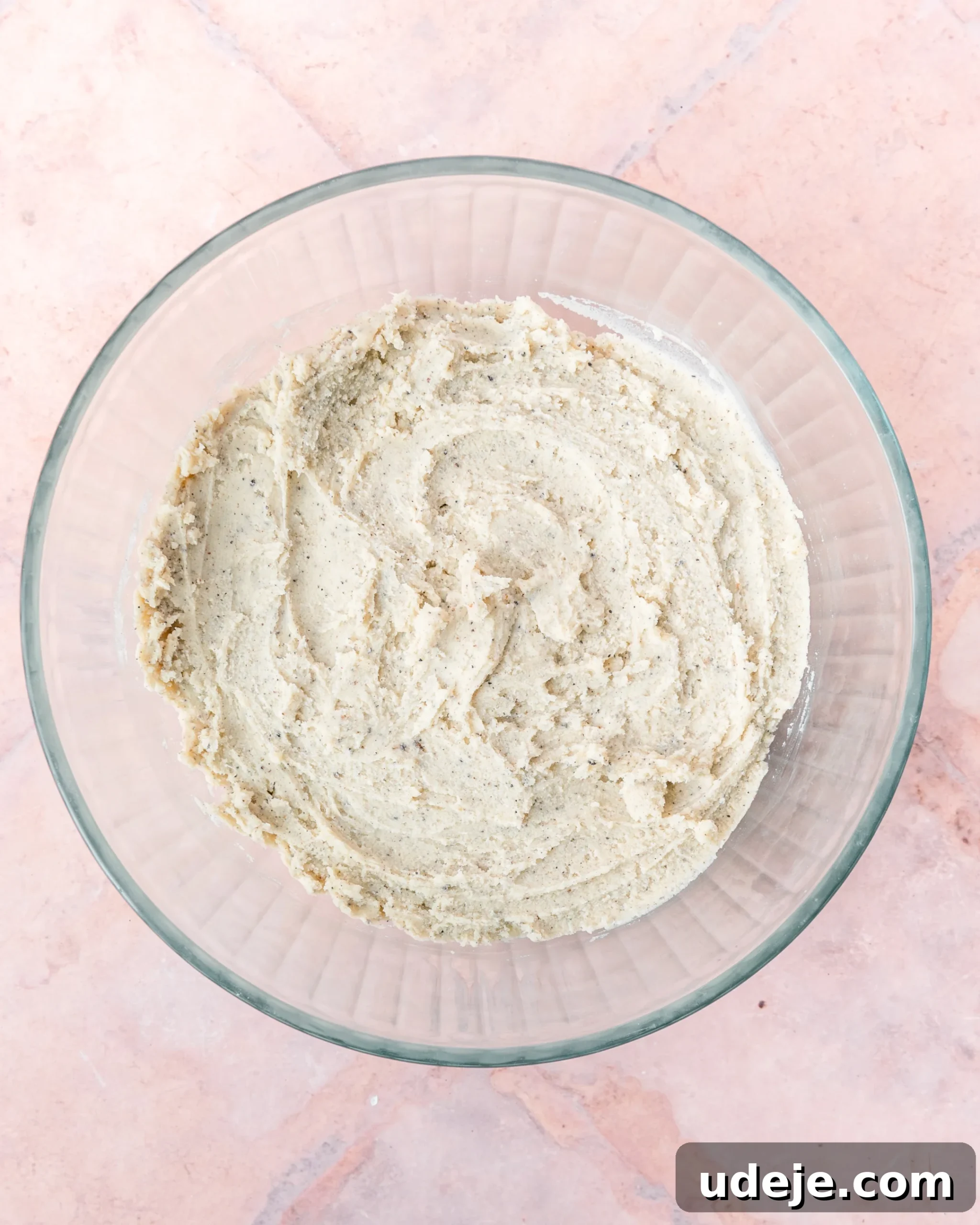 Fragrant Cardamom Shortbread Cookies 10 Cardamom shortbread dough in a glass bowl on light red tiled background.