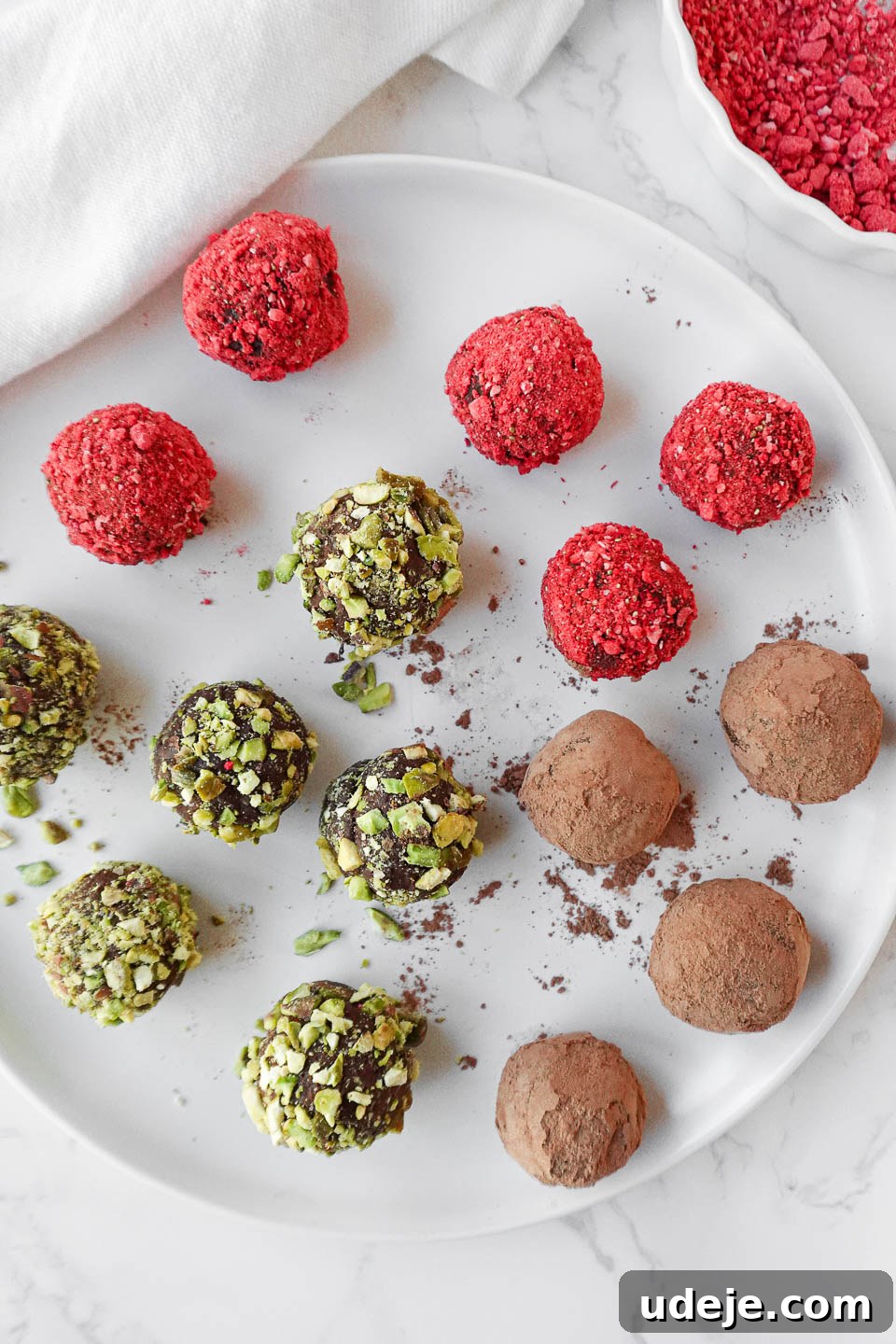 Velvet Avocado Chocolate Gems 5 A plate of vegan chocolate avocado truffles coated in cocoa powder, crushed pistachios, and freeze-dried strawberry powder