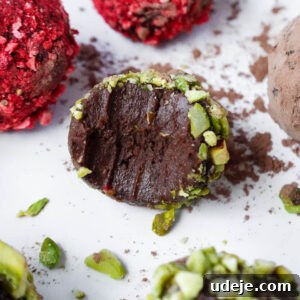 Velvet Avocado Chocolate Gems 6 Close-up of a chocolate avocado truffle with a bite taken out, revealing its creamy interior, coated in crushed pistachios.