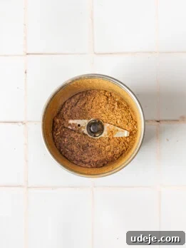 baharat spice blend in a spice grinder on a white tiled background
