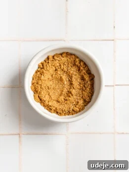 baharat spice blend in a white bowl on a white tiled background