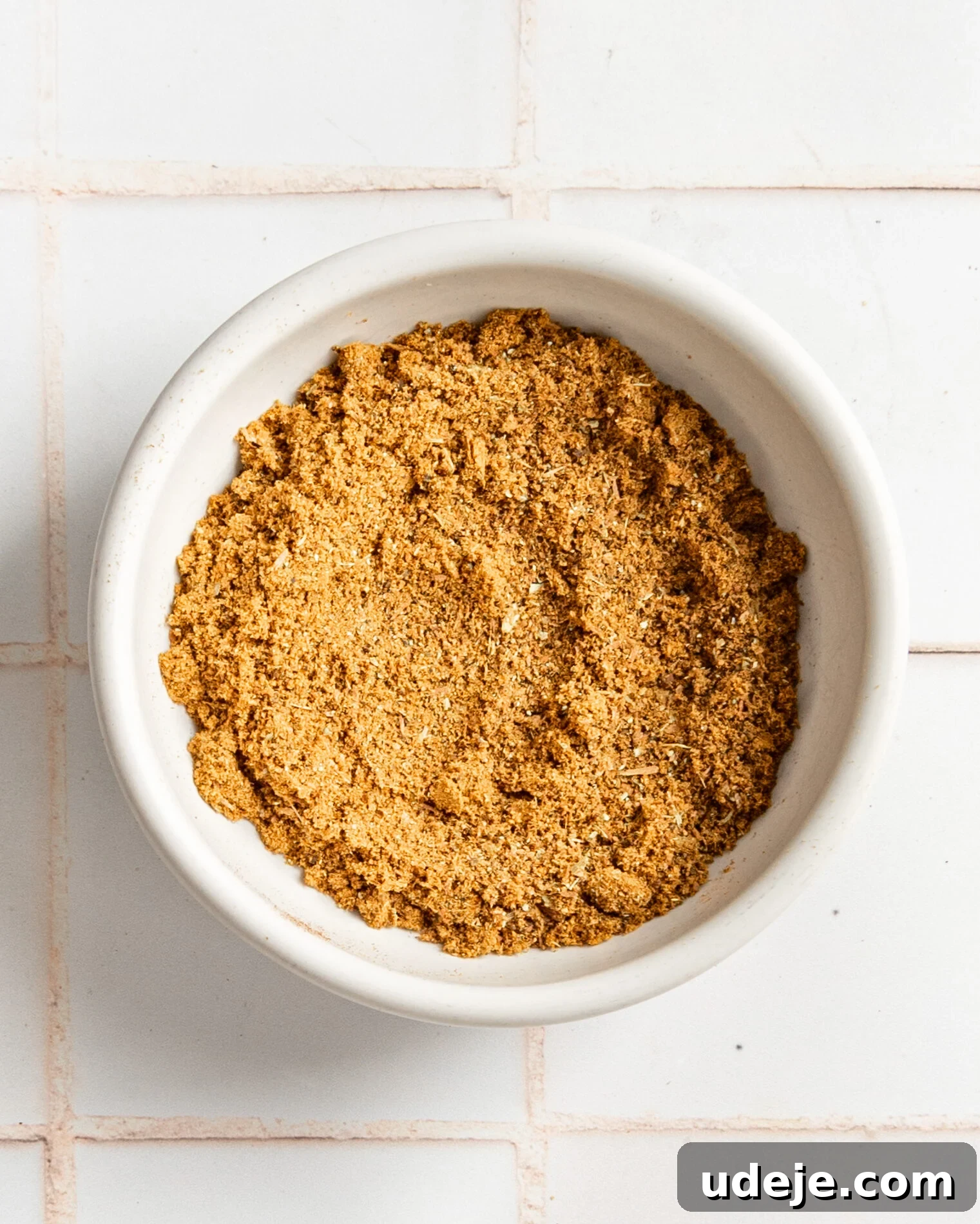 Handcrafted Baharat Mix 9 A serving of freshly prepared Baharat spice blend beautifully presented in a small white ceramic bowl, sitting on a pristine white tiled background.