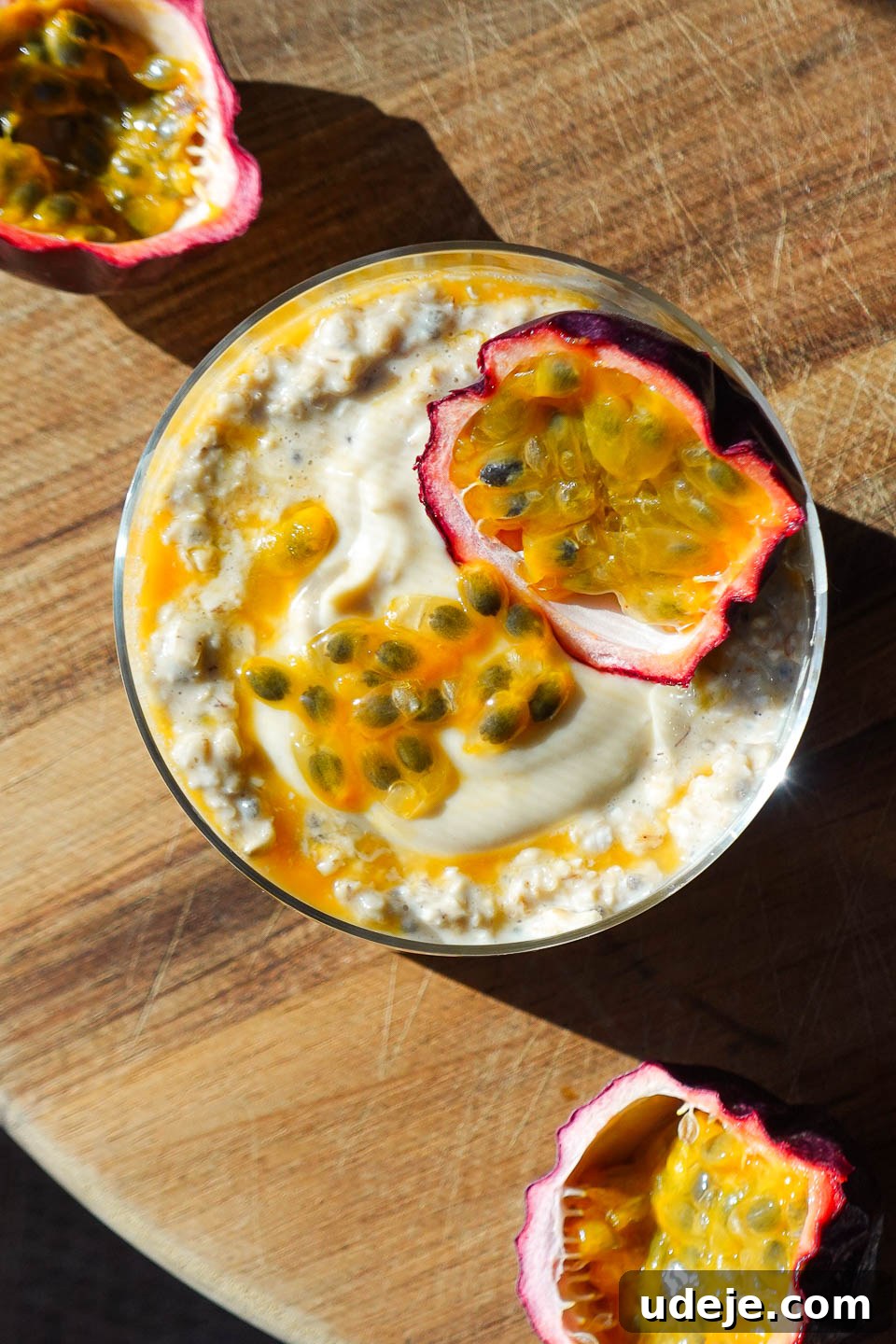 Tropical Mango Passion Overnight Oats 2 Overhead shot of tropical Mango & Passion Fruit Overnight Oats in a jar, garnished with a halved passionfruit and fresh mango cubes, highlighting its vibrant colors and creamy texture.