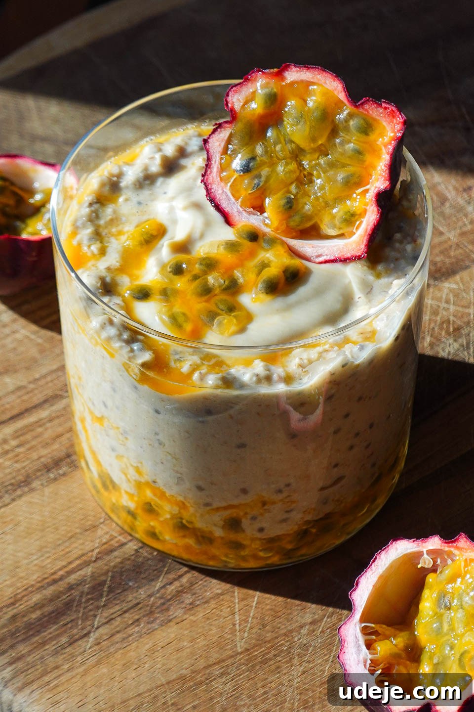 Tropical Mango Passion Overnight Oats 3 Close-up of Mango & Passion Fruit Overnight Oats in a glass jar, topped generously with passion fruit pulp, showcasing its vibrant orange and yellow hues and creamy texture.