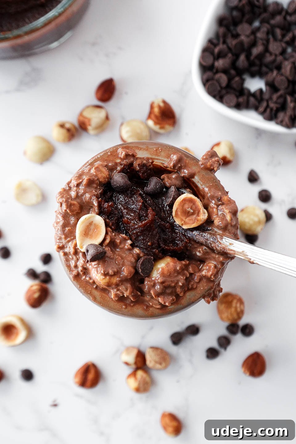 Dreamy Chocolate Hazelnut Overnight Delight 3 A spoon scooping up thick and creamy chocolate hazelnut overnight oats with dark chocolate chips and hazelnuts on top.