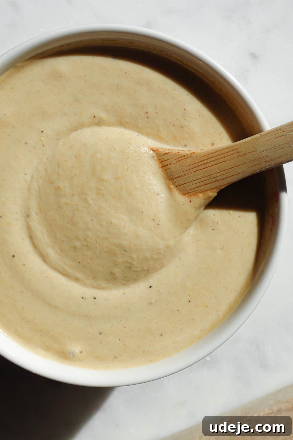 Bright Lemon Tahini Dressing 2 Smooth and creamy Lemon Tahini Dressing in a bowl with a wooden spoon, ready to be drizzled