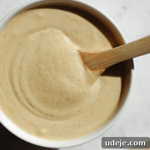 Smooth and creamy Lemon Tahini Dressing in a bowl with a wooden spoon