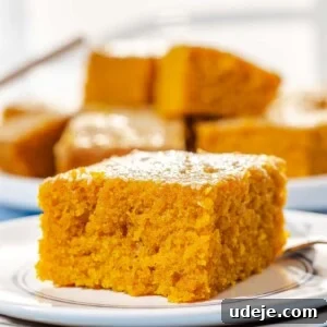 Aromatic Golden Semolina Cake 13 A single square of golden Sfouf cake beautifully presented on a blue and white patterned plate with a fork, against a soft blue background.