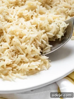 Instant Pot Basmati: Fluffy Perfection in 15 Minutes 18 Rice on a white plate with a spoon on a yellow tea towel.