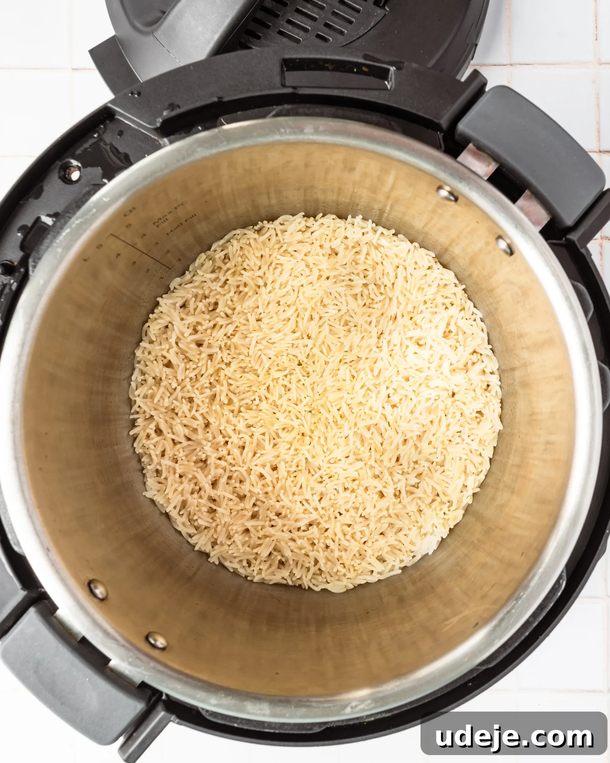Instant Pot Basmati: Fluffy Perfection in 15 Minutes 10 Freshly cooked, moist basmati rice filling the interior of the Instant Pot, showcasing its fluffy texture immediately after cooking, on a white tiled background.
