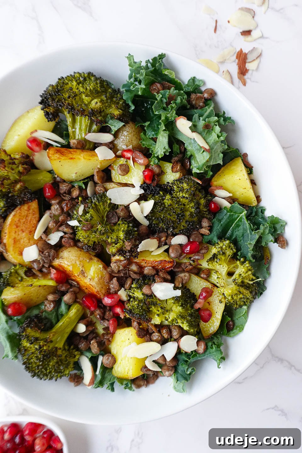 Nourishing Roasted Potato and Lentil Harvest Bowl 3 Healthy Roasted Potato & Lentil Buddha Bowl featuring golden potatoes, roasted broccoli, lentils, sautéed kale, and topped with pomegranate seeds, sliced almonds, and lemon tahini dressing.