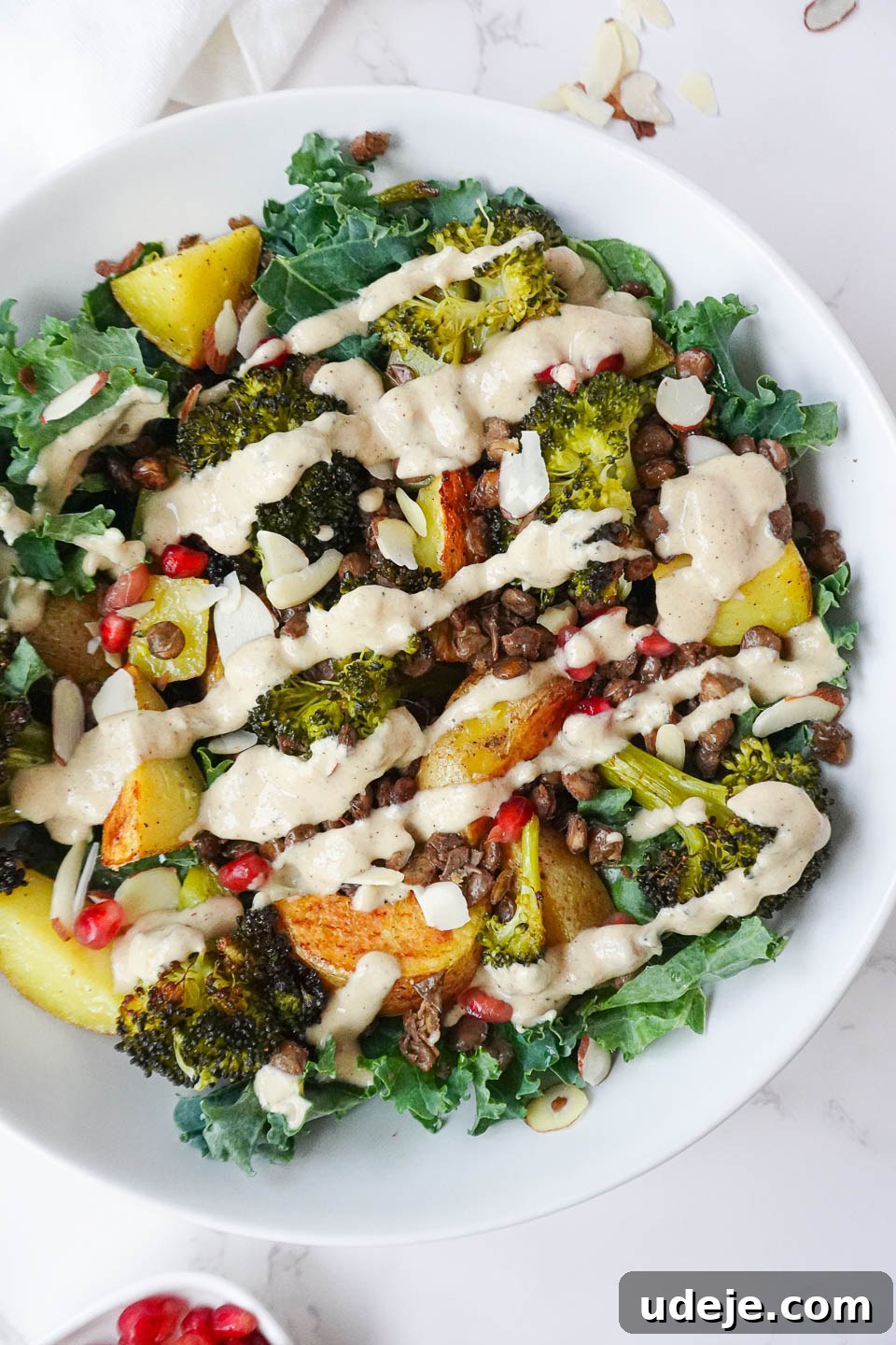 Nourishing Roasted Potato and Lentil Harvest Bowl 4 Delicious vegan Roasted Potato & Lentil Buddha Bowl with roasted vegetables, crispy lentils, and fresh kale, drizzled with creamy lemon tahini dressing and sprinkled with almonds and pomegranate seeds.