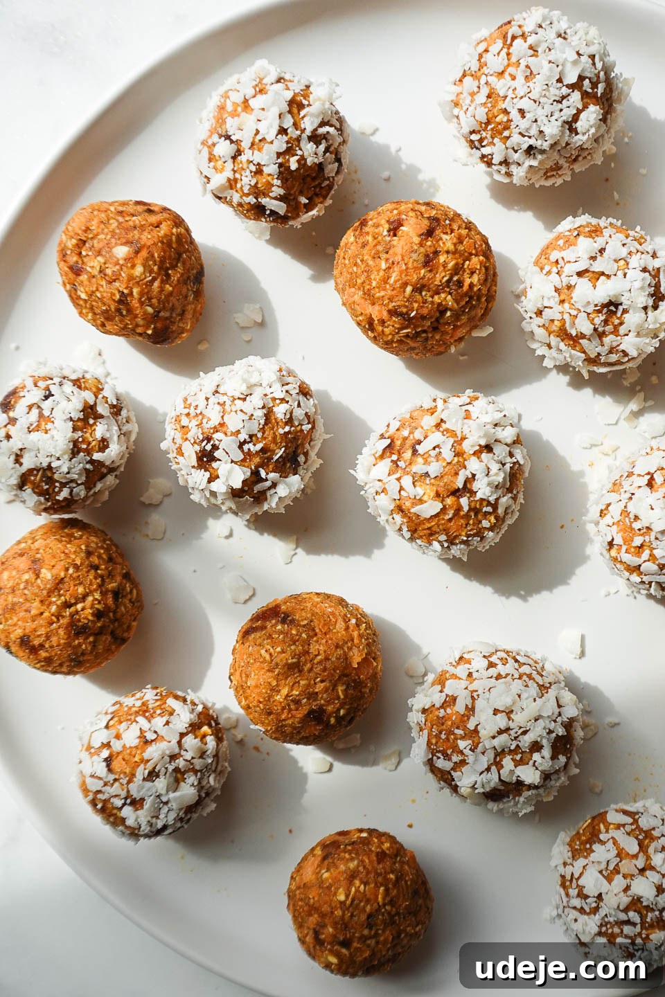 Carrot Cake Power Bites 5 A small pile of healthy carrot cake protein balls, coated in shredded coconut, neatly arranged on a white plate, ready to be eaten.