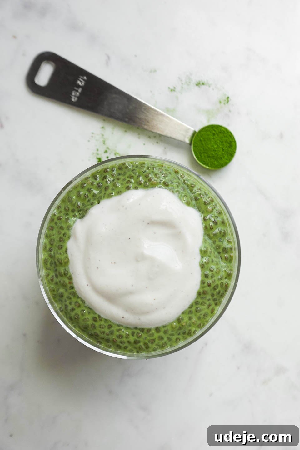 Energizing Matcha Chia Delight 2 Overhead shot of creamy matcha chia pudding in a glass jar topped with a swirl of vegan yogurt and a sprinkle of matcha powder, ready for a healthy breakfast.