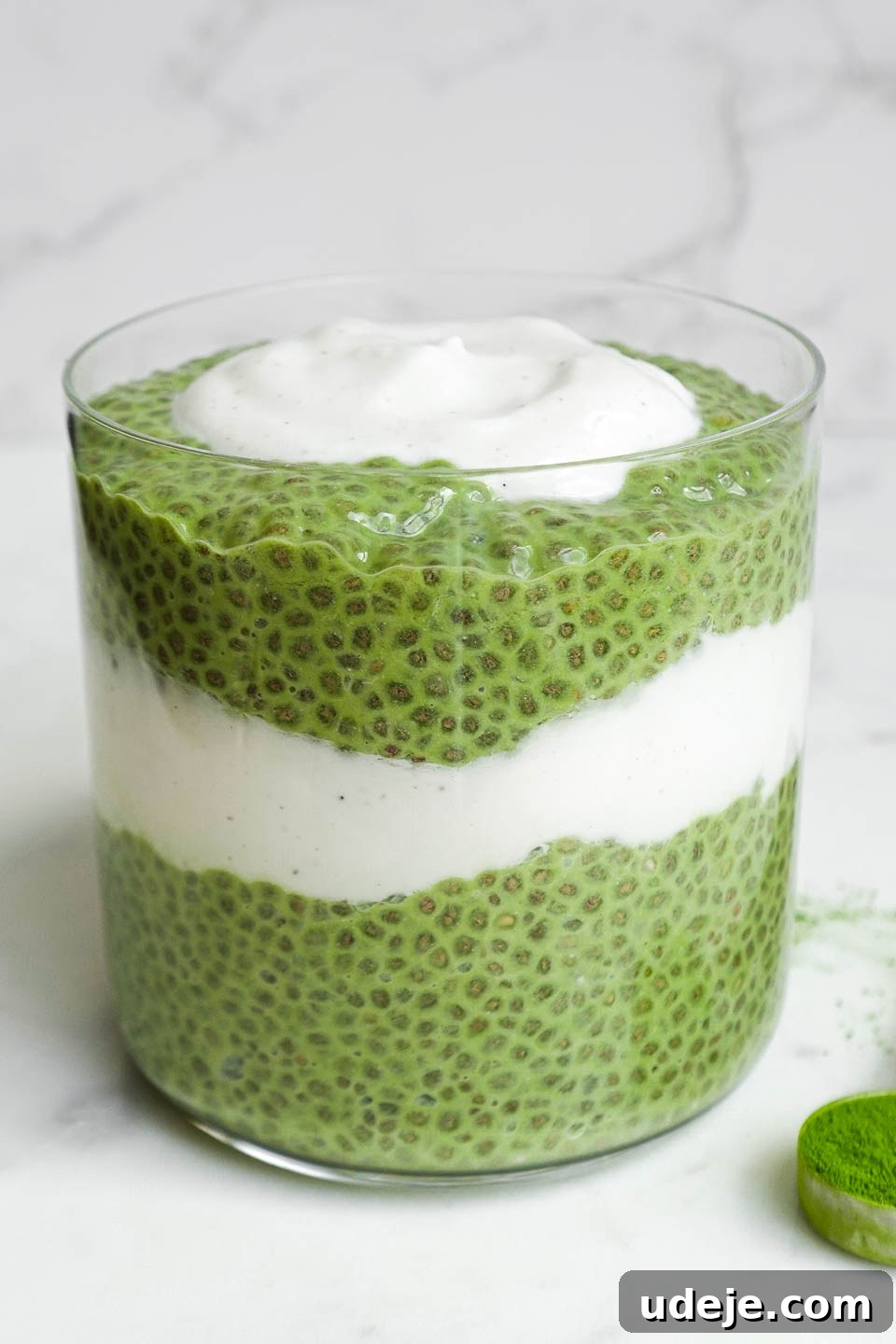 Energizing Matcha Chia Delight 5 Creamy green matcha chia pudding served in a clear glass jar, garnished with fresh berries and coconut flakes, ready for a nutritious breakfast.