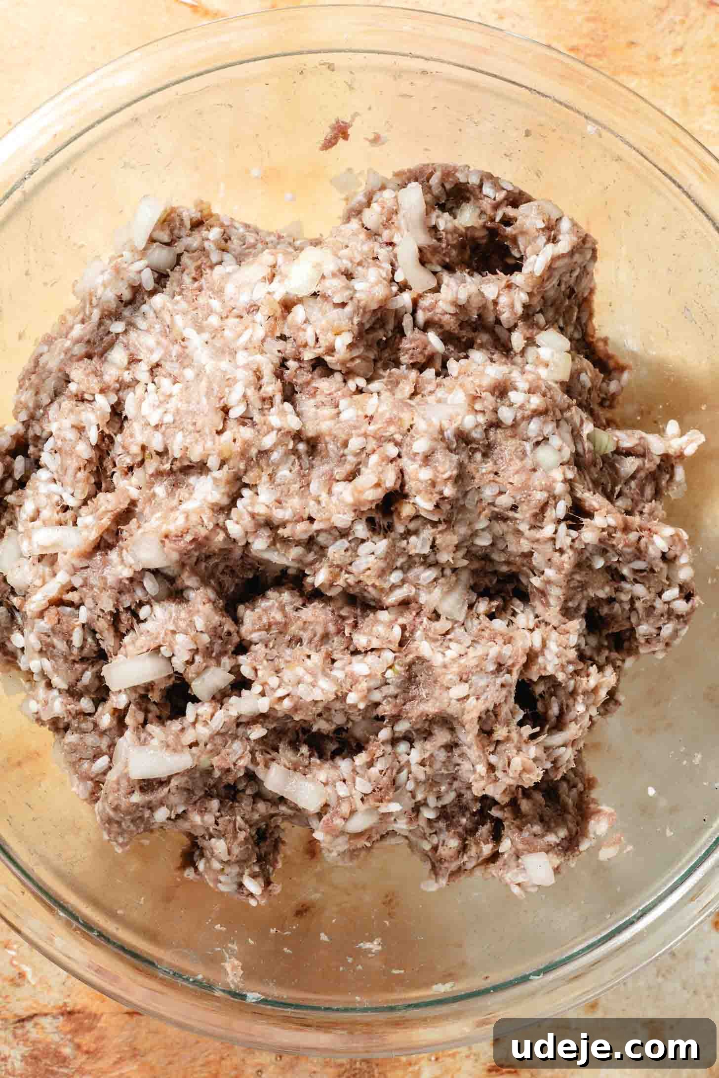 Irresistible Beef and Rice Cabbage Rolls 7 The ground beef mixture, expertly combined with rice, garlic, and spices, resting in a glass bowl on a rustic brown background, ready for stuffing.