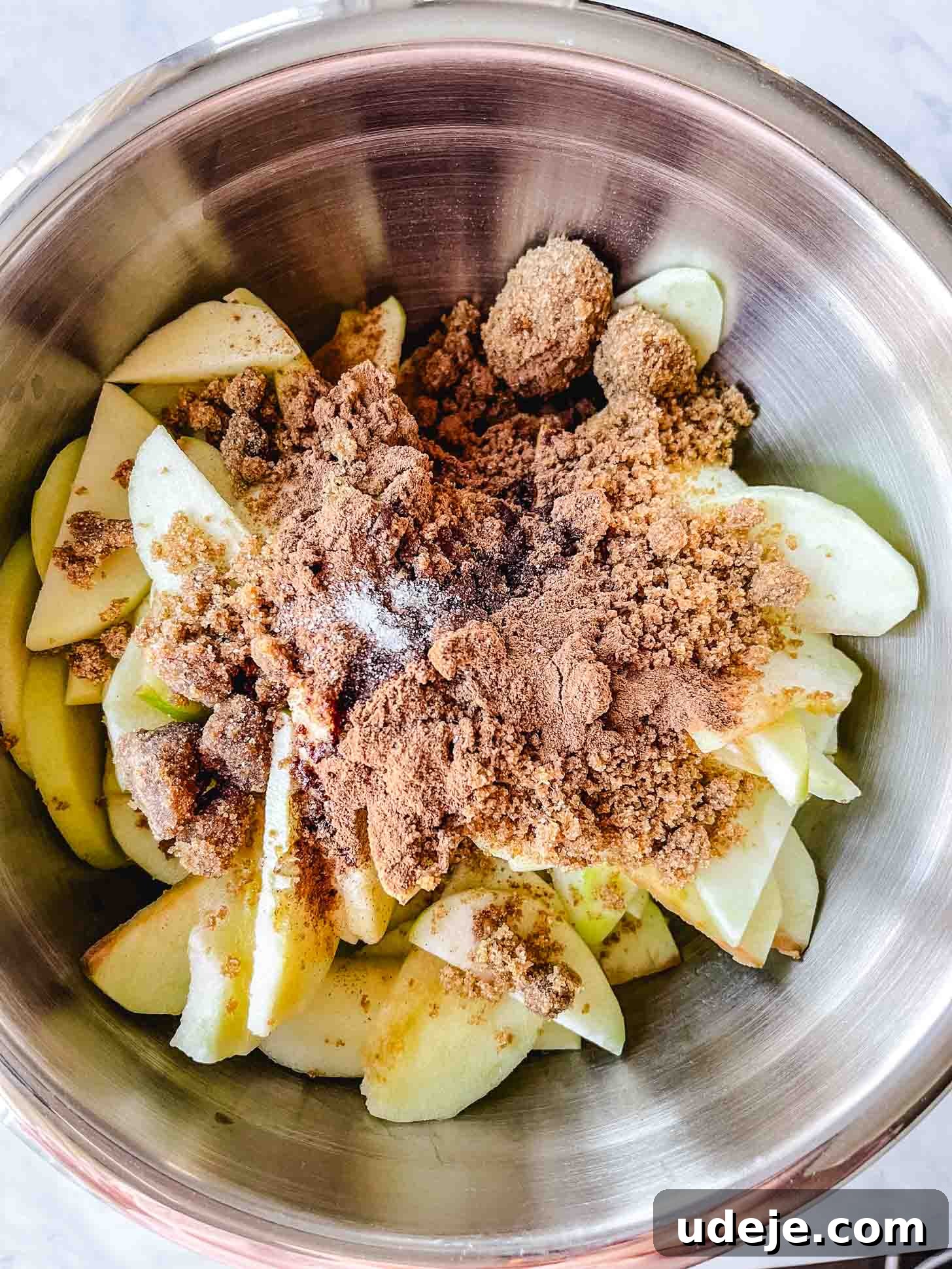 Apple Pie Meets Baklava 5 Sliced Granny Smith apples in a large steel bowl, seasoned with cinnamon, brown sugar, and salt.