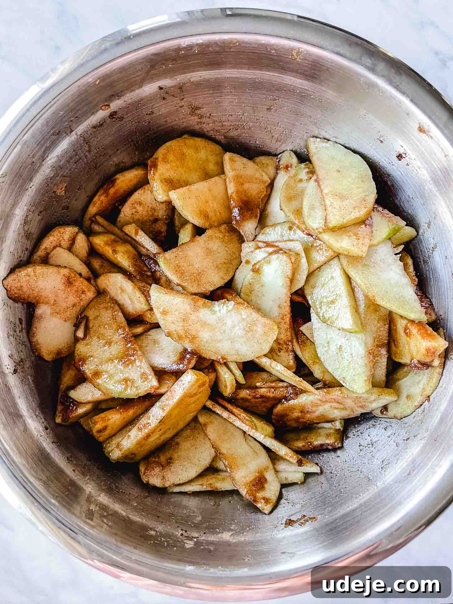 Apple Pie Meets Baklava 6 Sliced Granny Smith apples, mixed with brown sugar and cinnamon, sitting in a large steel bowl.