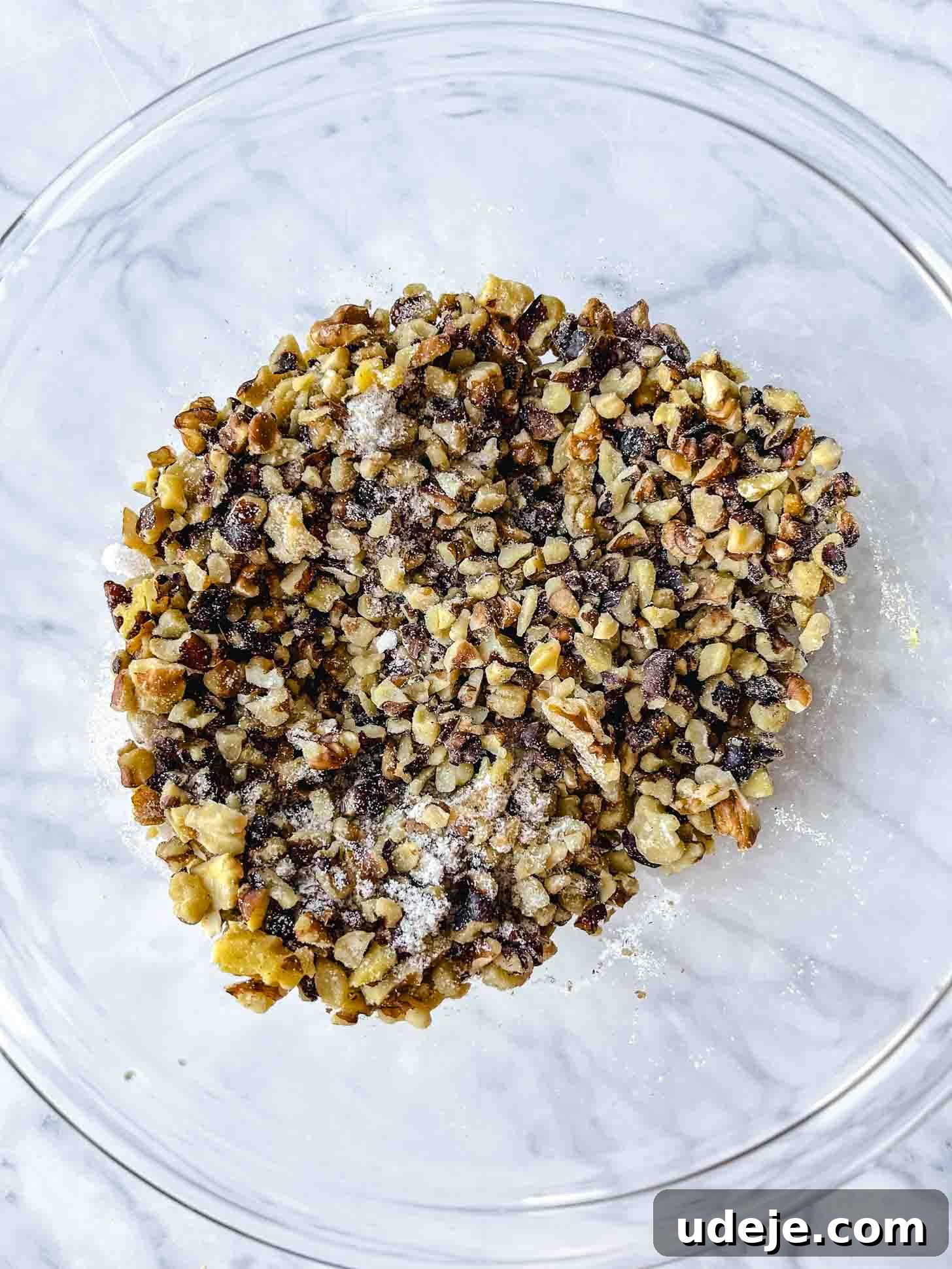 Apple Pie Meets Baklava 7 Chopped walnuts mixed with granulated sugar and spices in a clear glass bowl on a marble surface.