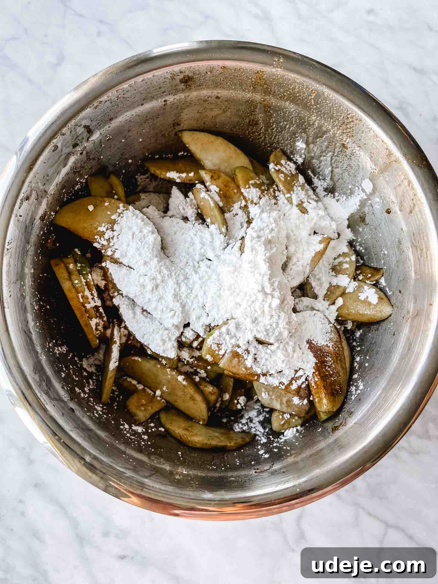 Apple Pie Meets Baklava 8 Sliced Granny Smith apples, mixed with brown sugar, cornstarch, and cinnamon, in a large steel bowl.