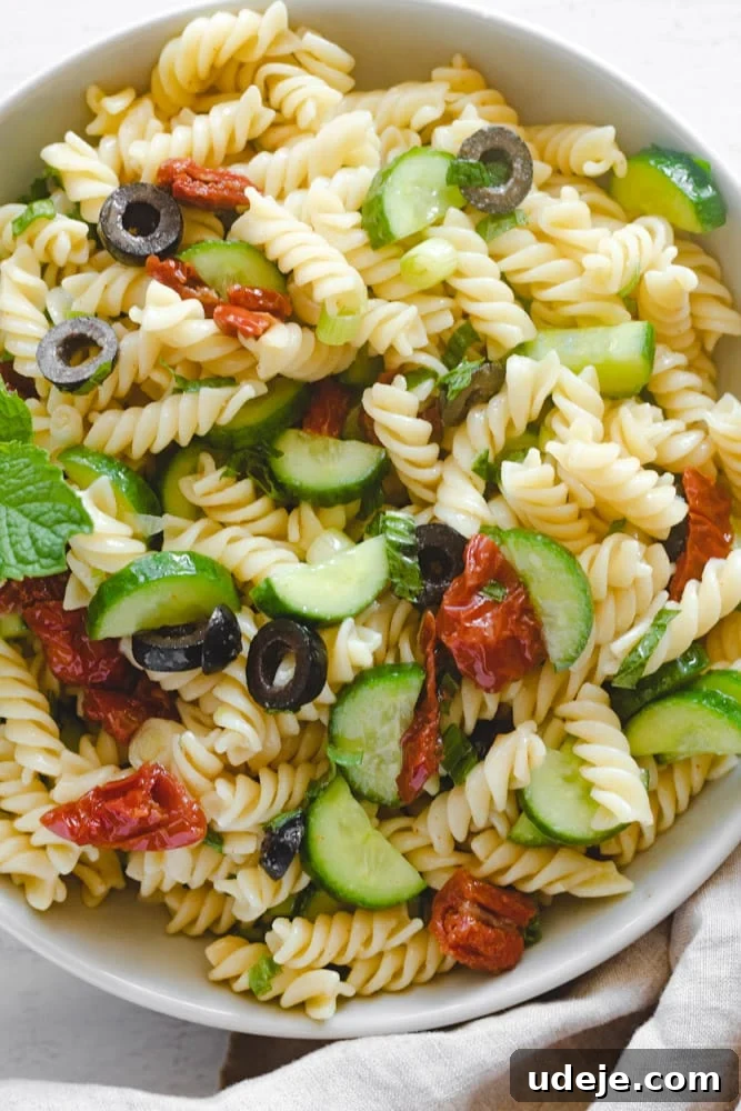 Vibrant Vegan Mediterranean Pasta Salad 3 Close-up of Vegan Mediterranean Pasta Salad in a bowl, showing texture and fresh ingredients like mint and olives.
