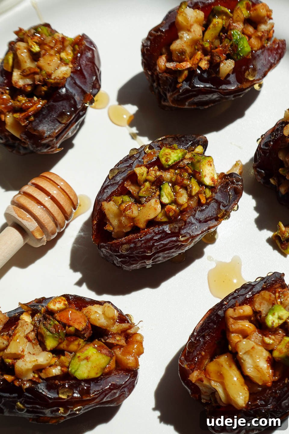 Gourmet Baklava-Filled Dates 2 Baklava stuffed medjool dates filled with pistachios, walnuts, and cinnamon arranged on a white plate.