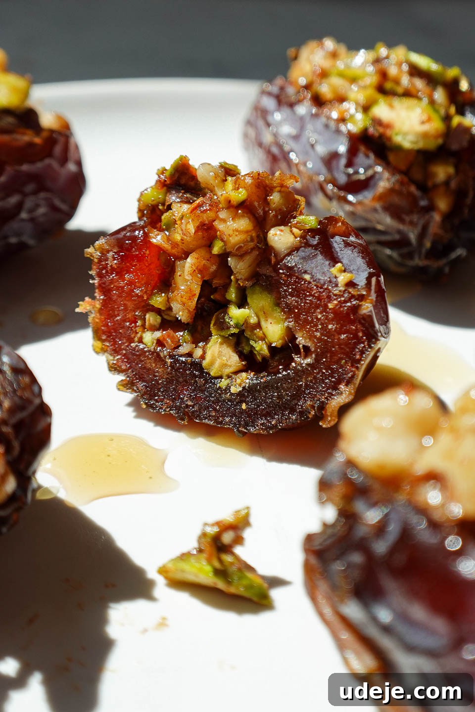 Gourmet Baklava-Filled Dates 4 Close-up of a baklava stuffed date with a bite taken out of it, showing the pistachio and walnut filling inside a soft medjool date