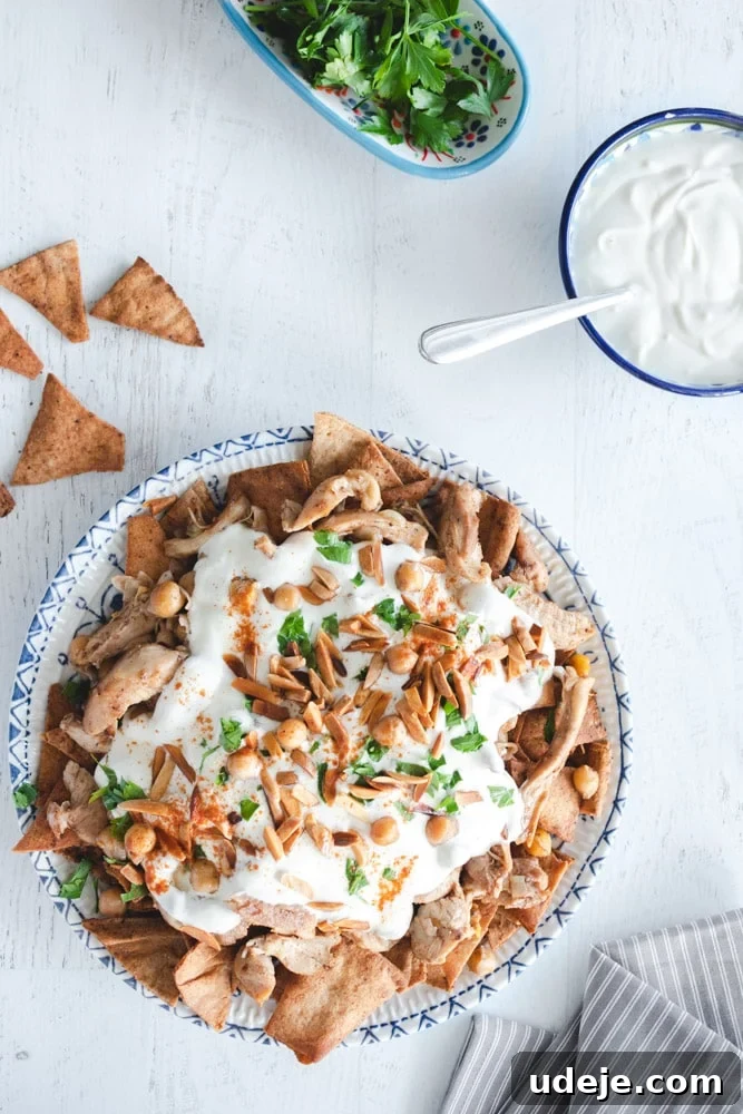 Effortless Chicken Fatteh Multiple Delicious Variations 2 Arabic chicken fatteh in a dish, garnished with taosted almonds and parsley