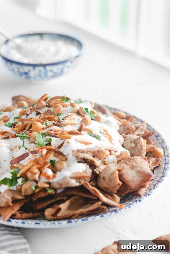 Effortless Chicken Fatteh Multiple Delicious Variations 3 Arabic chicken fatteh in a dish, garnished with taosted almonds and parsley