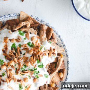Effortless Chicken Fatteh Multiple Delicious Variations 5 Arabic chicken fatteh in a dish, garnished with taosted almonds and parsley