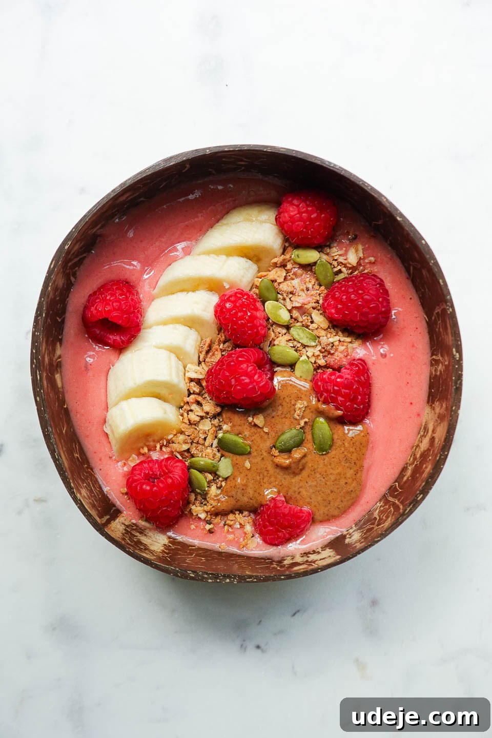 Simple and Delicious Vegan Raspberry Smoothie Bowl 4 Thick and creamy raspberry smoothie bowl with colorful toppings on a white background