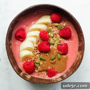 Thick and creamy raspberry smoothie bowl with colorful toppings on a white background