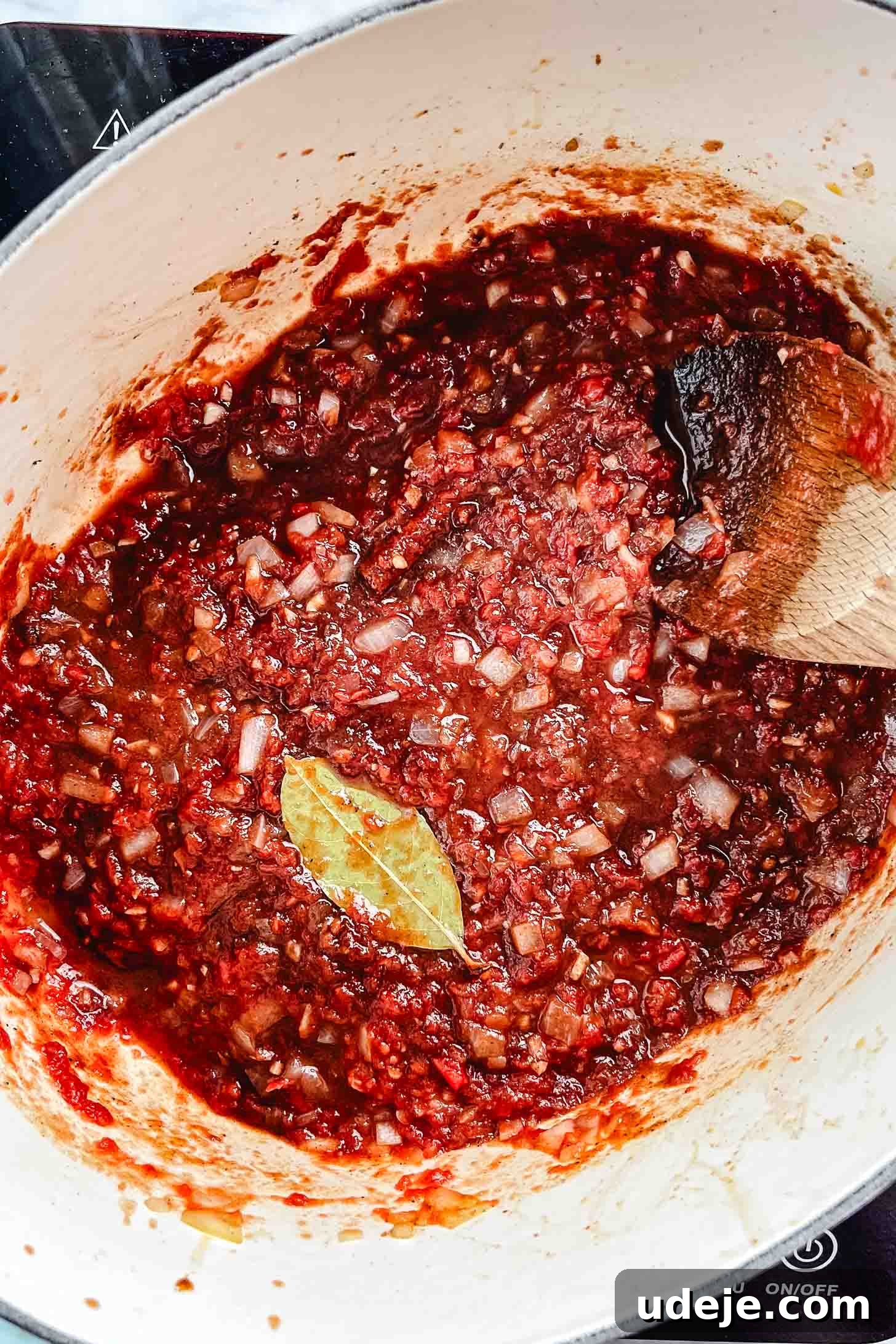 Melt-in-Your-Mouth Oven Braised Lamb Shanks 7 The aromatic base for the braising liquid comes together in an oval Dutch oven: cooked diced onions, a cinnamon stick, various spices, and a bay leaf are now combined with vibrant crushed tomatoes, ready for the next liquid additions.