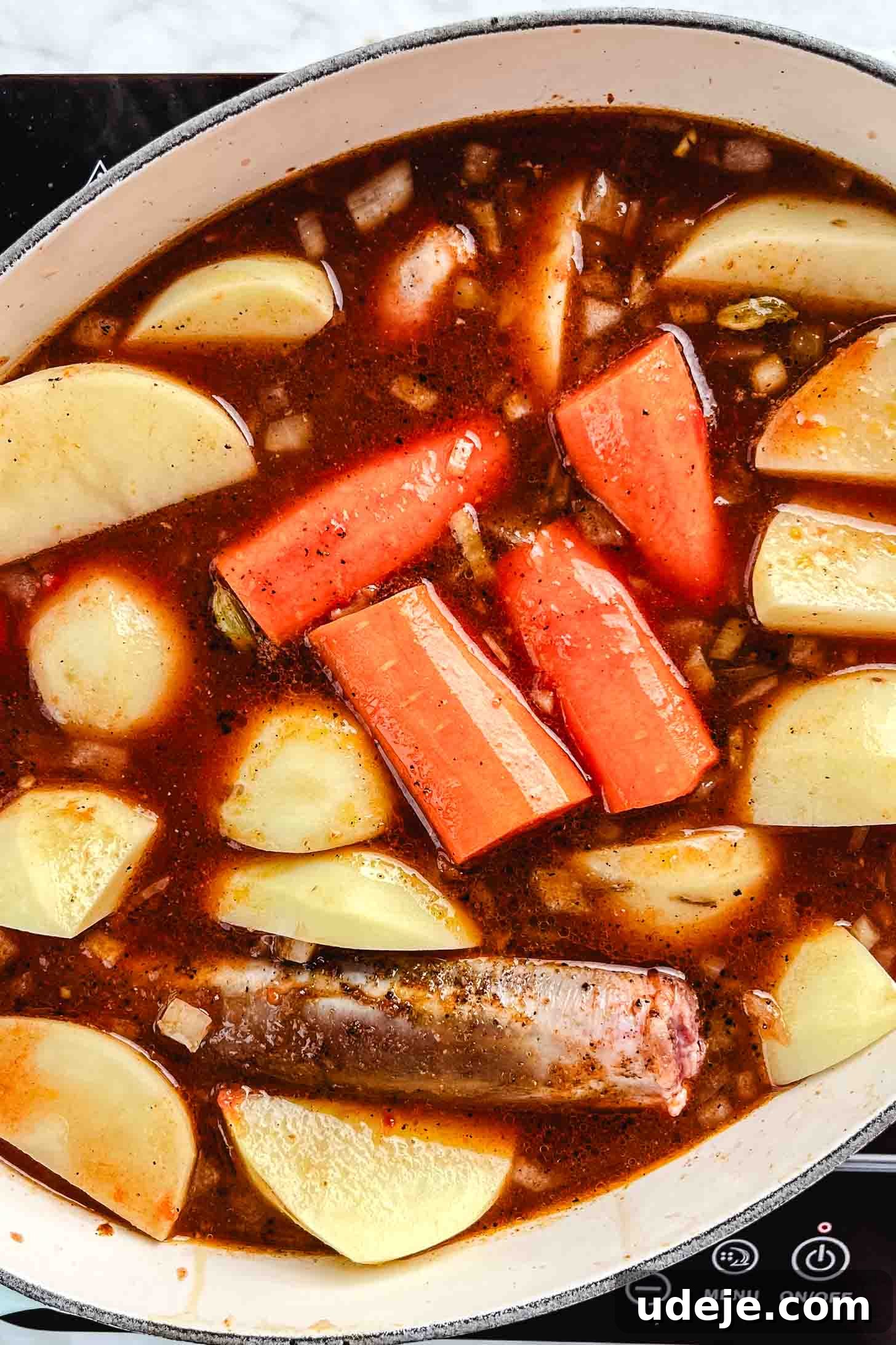 Melt-in-Your-Mouth Oven Braised Lamb Shanks 9 All elements are united in the oval pot: tender lamb shanks nestled within the fragrant braising liquid alongside substantial chunks of carrots and potato wedges, all topped with fresh thyme, ready for the oven.