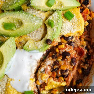 Plant Based Mexican Rice Bake 9 Close-up of a spoon scooping out casserole showing layers of rice, beans, corn, salsa, and creamy vegan queso