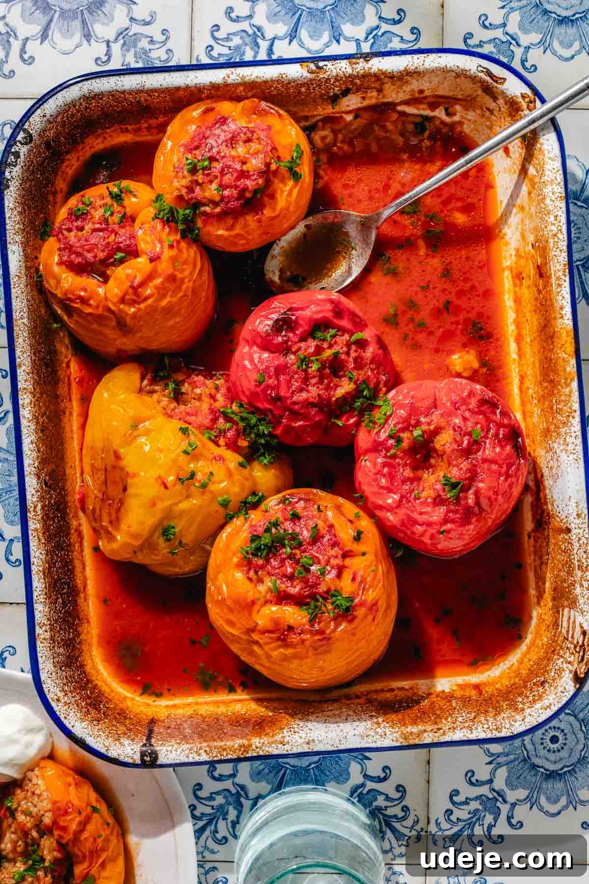 Mediterranean Veggie Stuffed Peppers 2 Baked yellow, orange and red bell peppers, stuffed with a rice mixture, placed in a large enamel baking dish with tomato sauce on the bottom, garnished with finely chopped parsley. A beautiful medley of colors promises a delicious meal.