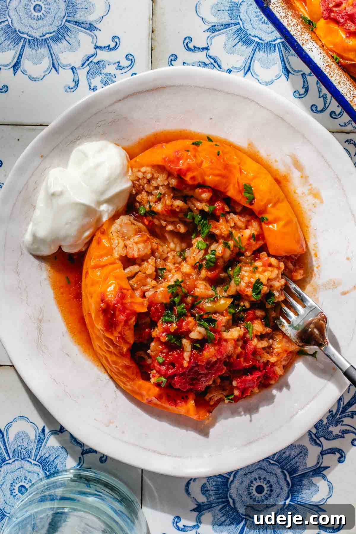 Mediterranean Veggie Stuffed Peppers 3 A large yellow bell pepper, stuffed with a rice mixture and baked, served on a small white plate with a fork and a dollop of yogurt.