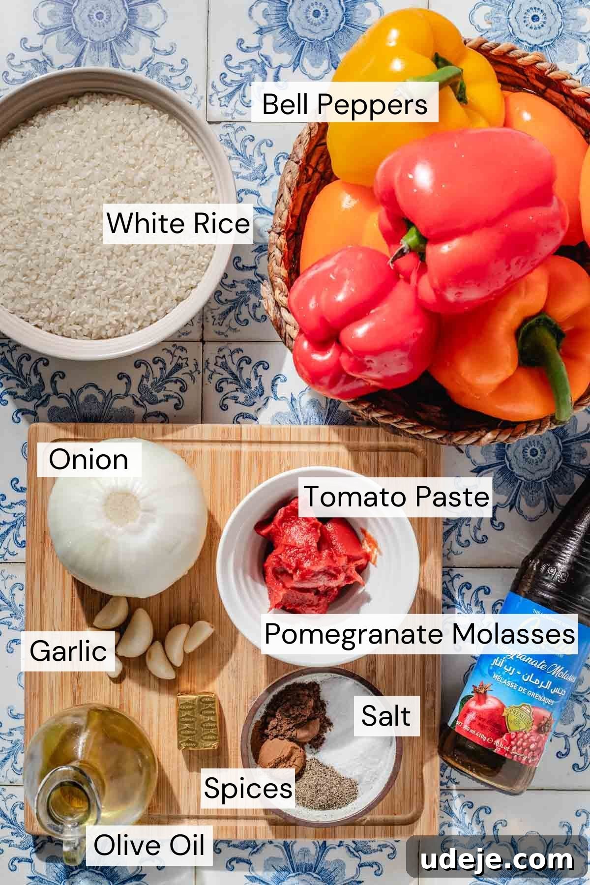 Mediterranean Veggie Stuffed Peppers 4 Ingredients needed for rice stuffed peppers, which include bell pepper, rice, onion, tomato paste, pomegranate molasses, garlic, spices, salt, and olive oil, laid out on a clean surface.