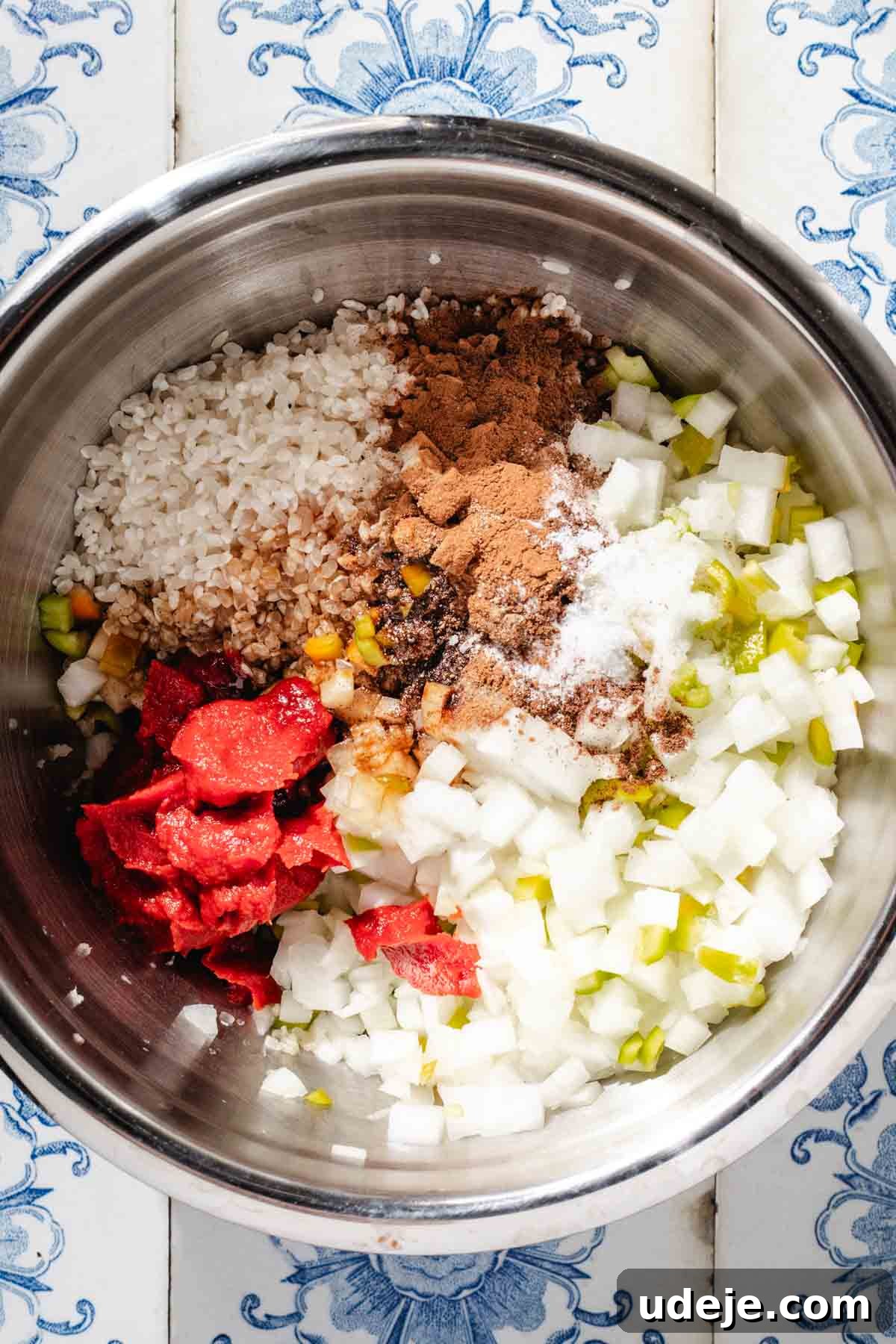 Mediterranean Veggie Stuffed Peppers 5 A mixture of uncooked white rice, chopped onions, chopped peppers, tomato paste, spices and olive oil in a large stainless steel mixing bowl
