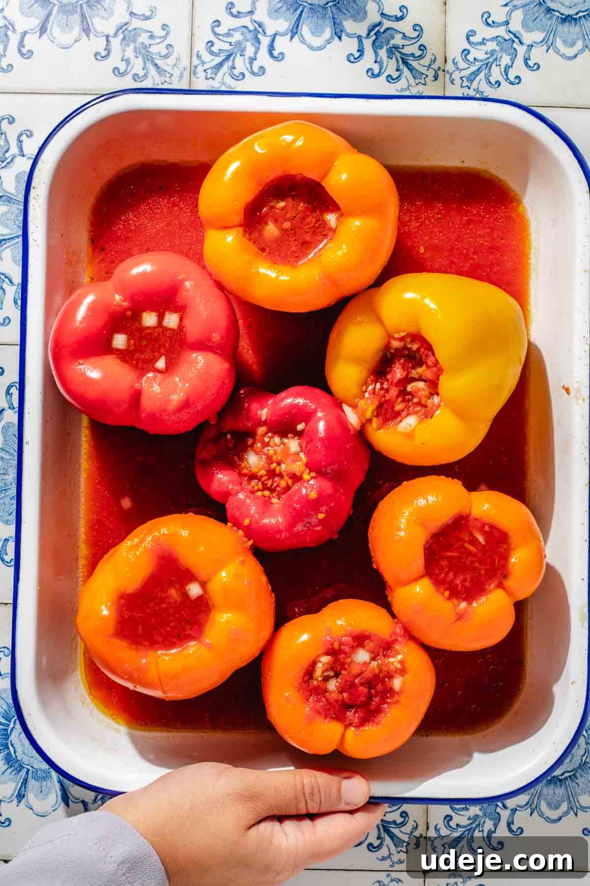 Mediterranean Veggie Stuffed Peppers 9 Large yellow, orange and red bell peppers, hollowed out and stuffed with a rice mixture, placed in a large enamel baking dish and with a red tomato sauce on the bottom.