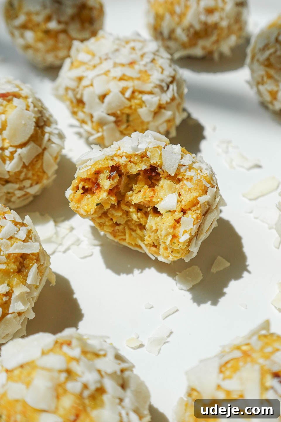Vegan No-Bake Mango Energy Bites 2 Close-up of a mango bliss ball with a chewy, coconut-covered texture, highlighting its vibrant color and tempting texture.