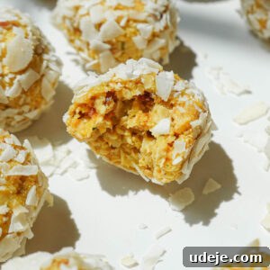 Close-up of a mango bliss ball with a chewy, coconut-covered texture.